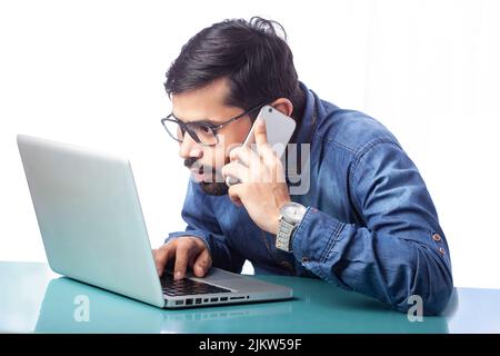 single person working on laptop and talking on mobile phone Stock Photo