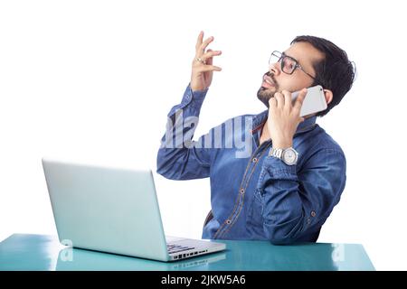 corporate man distracted from laptop work and talking on cell phone Stock Photo