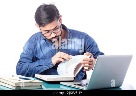 man reading something on diary while working on computer in isolated background Stock Photo