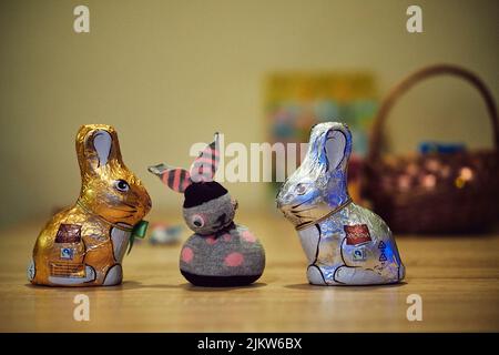 Two Favorina brand chocolate Easter bunnies and a sewn bunny on a table Stock Photo