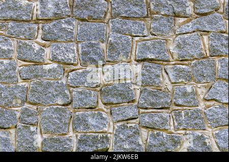 The texture of a stone wall made of immured granite cobblestones. Stock Photo