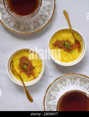 Two portions of saffron rice pudding served with cinnamon and tea. Stock Photo