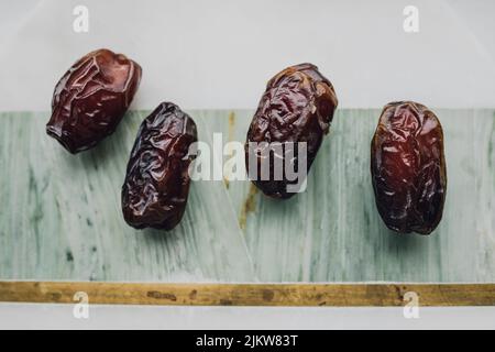 Four brown dates, fruit on green, marble, brass cheese board Stock Photo