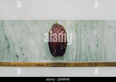 single date, fruit on green, marble, brass cheese board Stock Photo
