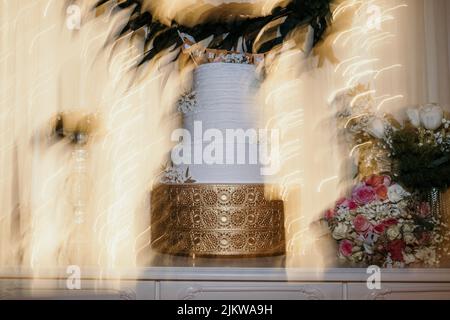 A beautiful white wedding cake on a golden stand Stock Photo