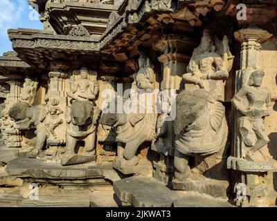 Stock photo of ruined ancient sculpture of Hindu trinity god sitting on elephant, idol carved out off gary color granite sunlight falling on idol, Pic Stock Photo