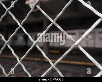 Metal fence with boke of subway passing by in the background Stock Photo