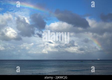 A beautiful rainbow in the cloudy sky over the ocean Stock Photo