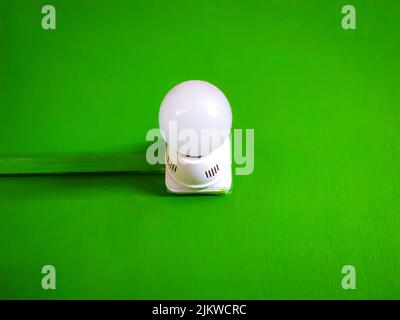 A closeup shot of a light bulb with a white plastic lamp holder isolated on a green chroma background Stock Photo