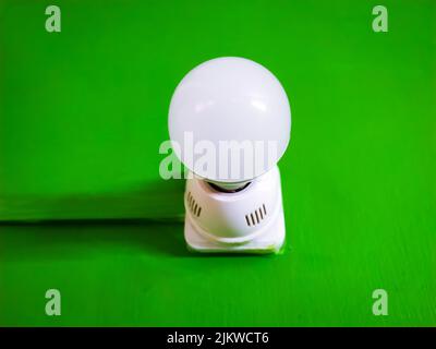 A closeup shot of a light bulb with a white plastic lamp holder isolated on a green chroma background Stock Photo