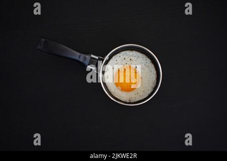 Fried eggs in a pan and a black background Stock Photo