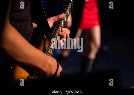 A selective focus shot of a man playing an electric guitar on the stage Stock Photo