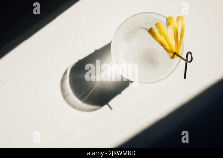 directly above, soda water with ice and cut lemon peel garnish on cocktail pick in the sun Stock Photo