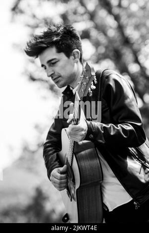 boy plays black and white guitar in nature Stock Photo