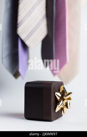 Vertical close up of a brown gift on a white background with colorful ties. Stock Photo