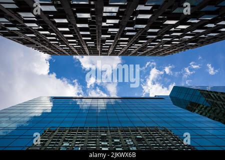 Looking towards a bright sky between two modern skyscrapers in London with clouds passing overhead. Stock Photo