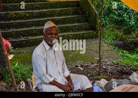 Kolhapur ,India- September 15th 2019; stock photo of 50 to 60 age group Indian man wearing white shirt, pant and cap, selling farm, fresh fruits in th Stock Photo