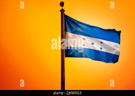 The national flag of Laos on a flagpole isolated on an orange background Stock Photo