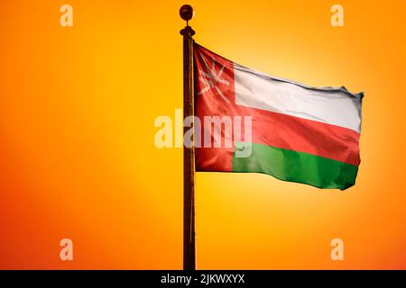 The national flag of Oman on a flagpole isolated on an orange background Stock Photo