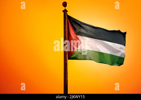The national flag of Palestine on a flagpole isolated on an orange background Stock Photo