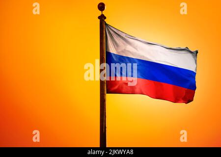 The national flag of Russia on a flagpole isolated on an orange background Stock Photo