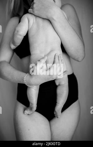 A vertical shot of a mother holding her newborn baby in grayscale Stock Photo