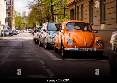 Historic oldtimer VW Beetle with orange paint. The classic car is located in the central city of Munich and fits well into the historical scenery Stock Photo