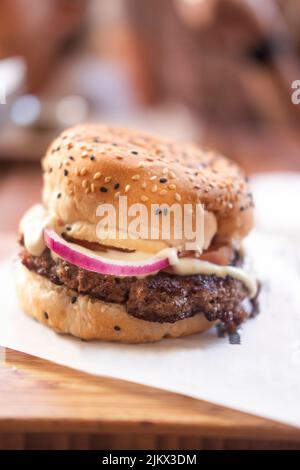 A vertical closeup of a delicious hamburger with onions, mayo and buns with seeds Stock Photo