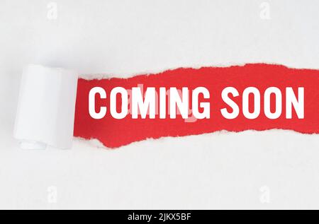 Business and finance. Behind torn white paper on a red background, the text - COMING SOON Stock Photo