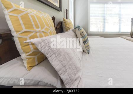 Decorative pillows on a large bed in a light and airy master bedroom Stock Photo