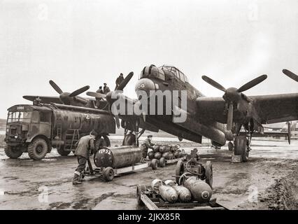 Ground crews refuelling and bombing up an Avro Lancaster of No. 75 (New Zealand) Squadron RAF at Mepal, Cambridgeshire, England, for a night raid on Krefeld, Germany. The bomb load consists of a 4,000-lb HC 'cookie' and mixed 1,000-lb and 500-lb MC bombs. The 'Lancs' first saw service with RAF Bomber Command in 1942 and as the strategic bombing offensive over Europe gathered momentum, it became the main aircraft for the night-time bombing campaigns that followed. Stock Photo