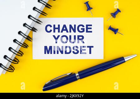 Business and finance concept. On a yellow background lies a notebook, a pen and a business card with the inscription - CHANGE YOUR MINDSET Stock Photo