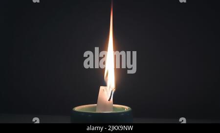 A closeup of a candle lighting up and illuminating in the darkness Stock Photo