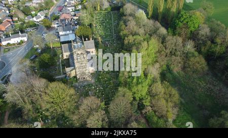 A bird's eye view of a small-town church ad cemetery surrounded by green fields and trees Stock Photo