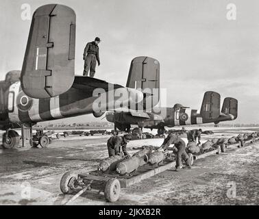RAF and Dutch naval ground crews prepare to load 500-lb MC bombs into North American Mitchell Mark IIs of No. 98 Squadron RAF, during wintry conditions in Belgium. The North American B-25 Mitchell was a medium bomber introduced in 1941 and used by many Allied air forces. Stock Photo