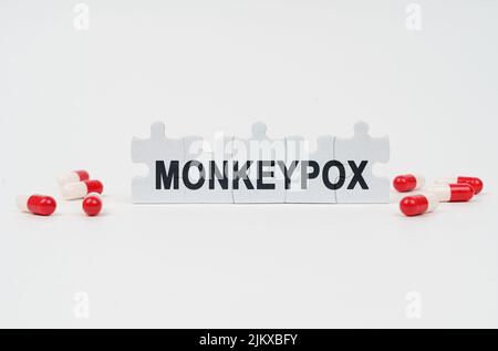 Medical concept. On a white surface are tablets and puzzles with the inscription - monkeypox Stock Photo