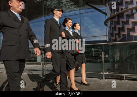 Two young flight attendants walking with pilots outdoor Stock Photo