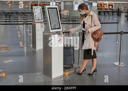 Young female touching interactive screen to check in online in airport Stock Photo