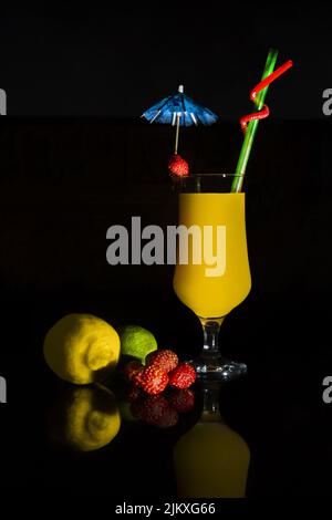 A vertical closeup of a fruit cocktail isolated on dark background. Stock Photo