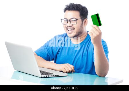 cheerful man holding credit card and smiling in front of a laptop Stock Photo