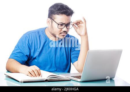 corporate man wearing glass using laptop and writing on notebook Stock Photo