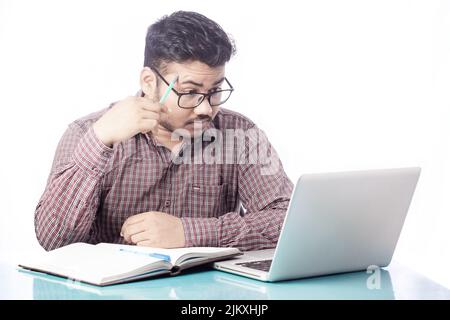young man wearing eyeglass thinking and planning looking at laptop screen Stock Photo