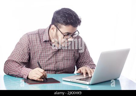 3d artist drawing with digital graphic tablet and stylus pen on laptop looking over eyeglass Stock Photo