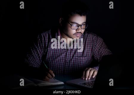 dedicated student studying online course at late night using laptop Stock Photo