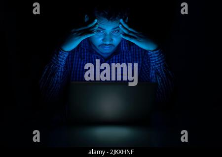 corporate employee feeling tired and headache while working late night on laptop Stock Photo