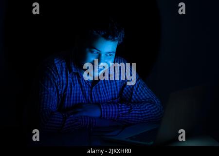 young man watching something on laptop at late night Stock Photo