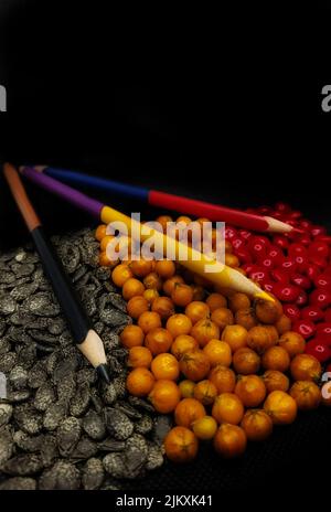 Red, yellow, and black color pencils with the same color seeds Stock Photo
