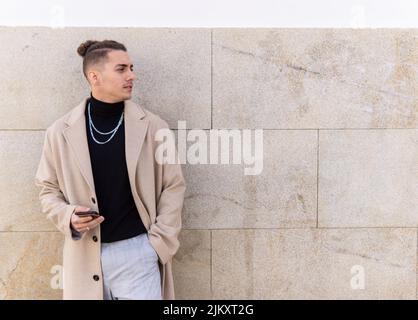 Portrait of a young mixed-race man holding a smartphone in the city. Social media, communication, mobile apps, business, lifestyle concept Stock Photo
