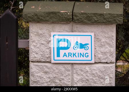 A motorcycle parking sign on stone wall Stock Photo