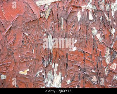 Chipboard in red paint. Background from a painted board. Pattern. Wooden background. Compressed chips. Old shabby wall. peeling paint Stock Photo